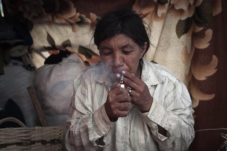 Gypsy woman lightening a cigarette made of journal paper