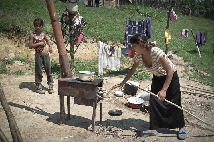 Gipsy woman prepairing a meal on a wood-fired stove outdoors