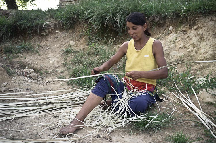 Gypsy woman prepairing rods for braiding a basket