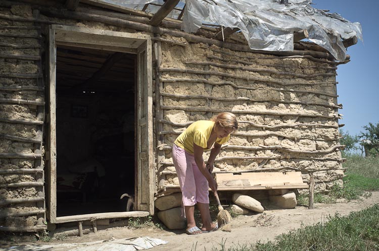 Gipsy woman cleaning the ground outside her clay hut